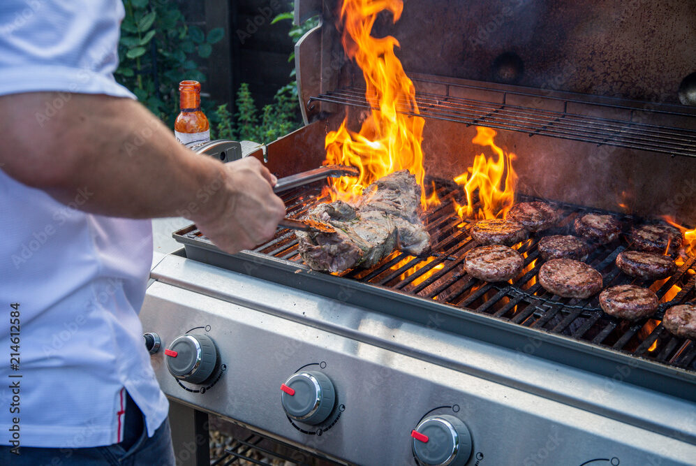 man cooking steaks on a grill