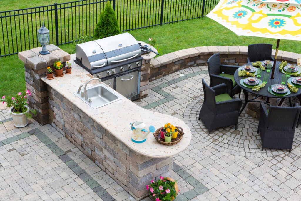 A bird’s eye view of an outdoor kitchen and black outdoor furniture, with beautiful foliage and greenery.