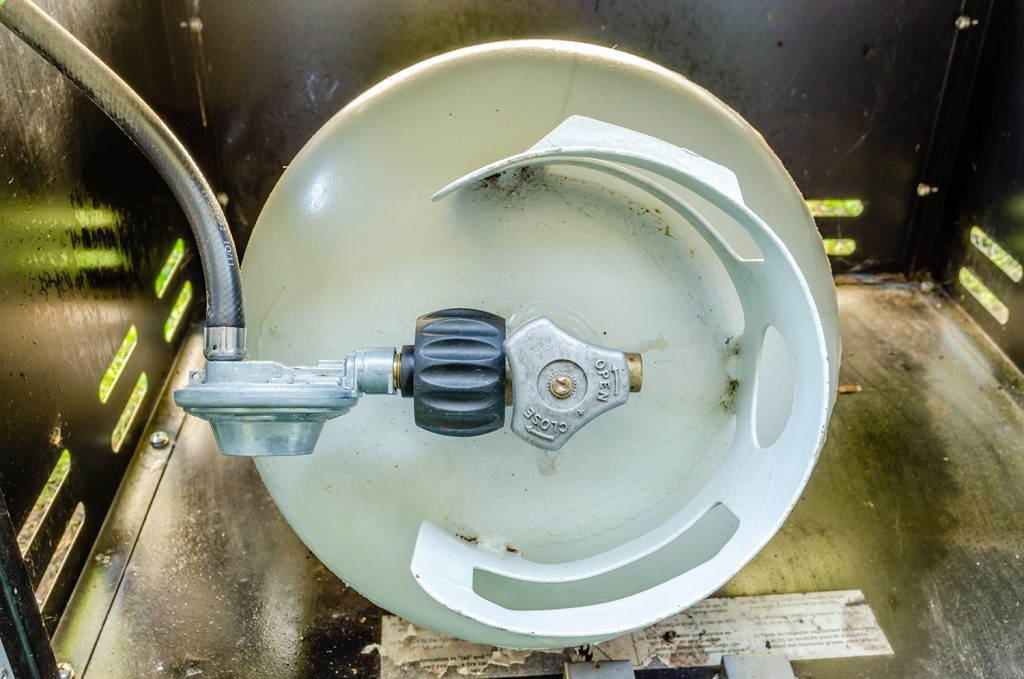 A gas grill propane tank tilted to display