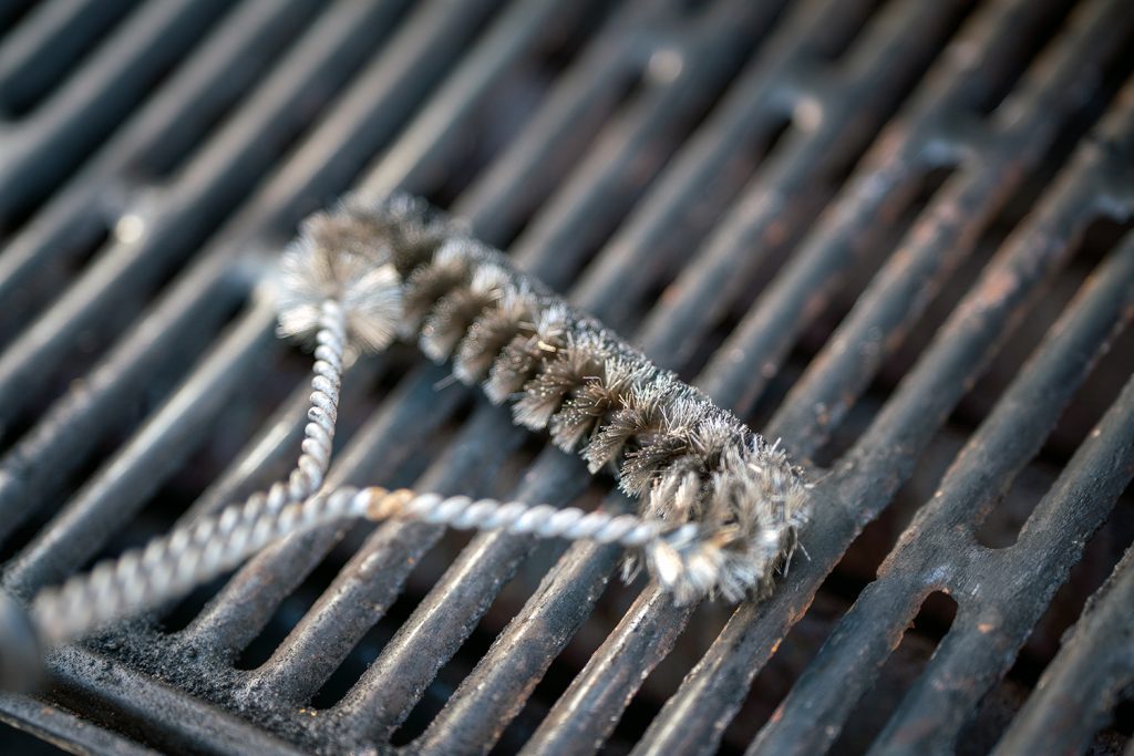 A wire brush being used on a cooking grate